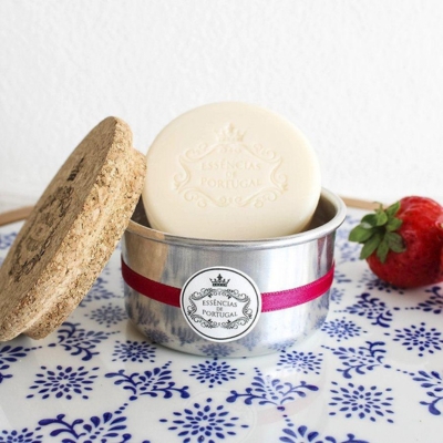 Sabonete branco em caixa metálica com tampa de cortiça e morango ao lado