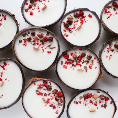 Velas brancas em cascas de coco com decoração colorida sobre fundo branco