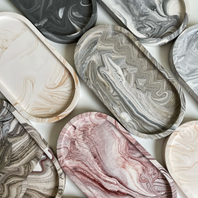 Tabuleiros marmoreados em várias cores e formatos dispostos sobre superfície clara