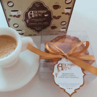 chávena branca de café com pires, caixa castanha decorativa e sabonete em caixa transparente com laço