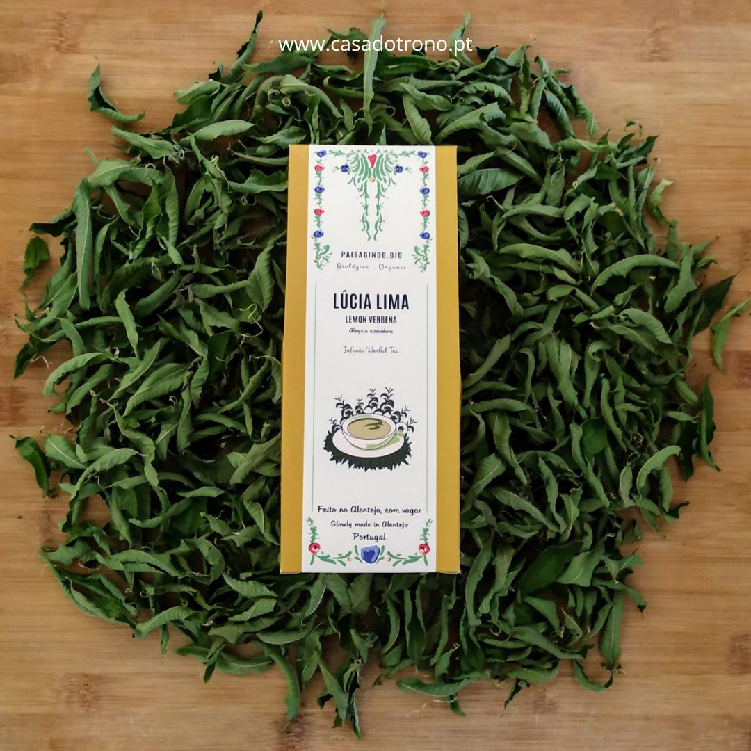 Embalagem de erva seca Lúcia Lima sobre folhas secas em fundo de madeira