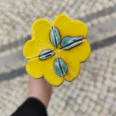 Flor amarela decorativa em cerâmica com detalhes azuis e pretos