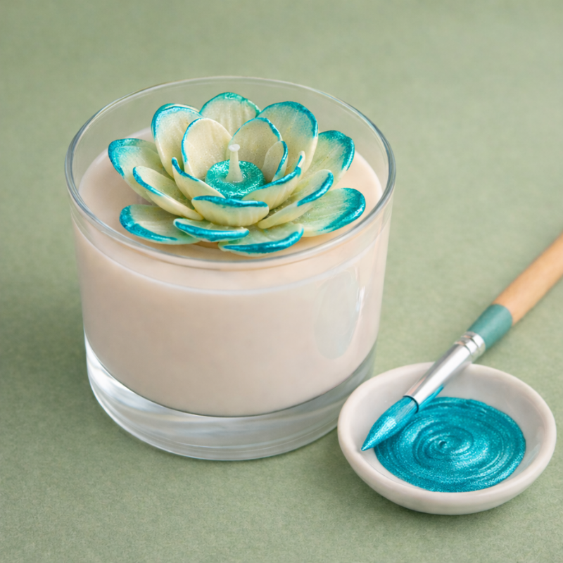 Vela com flor decorativa azul e pincel com tinta azul