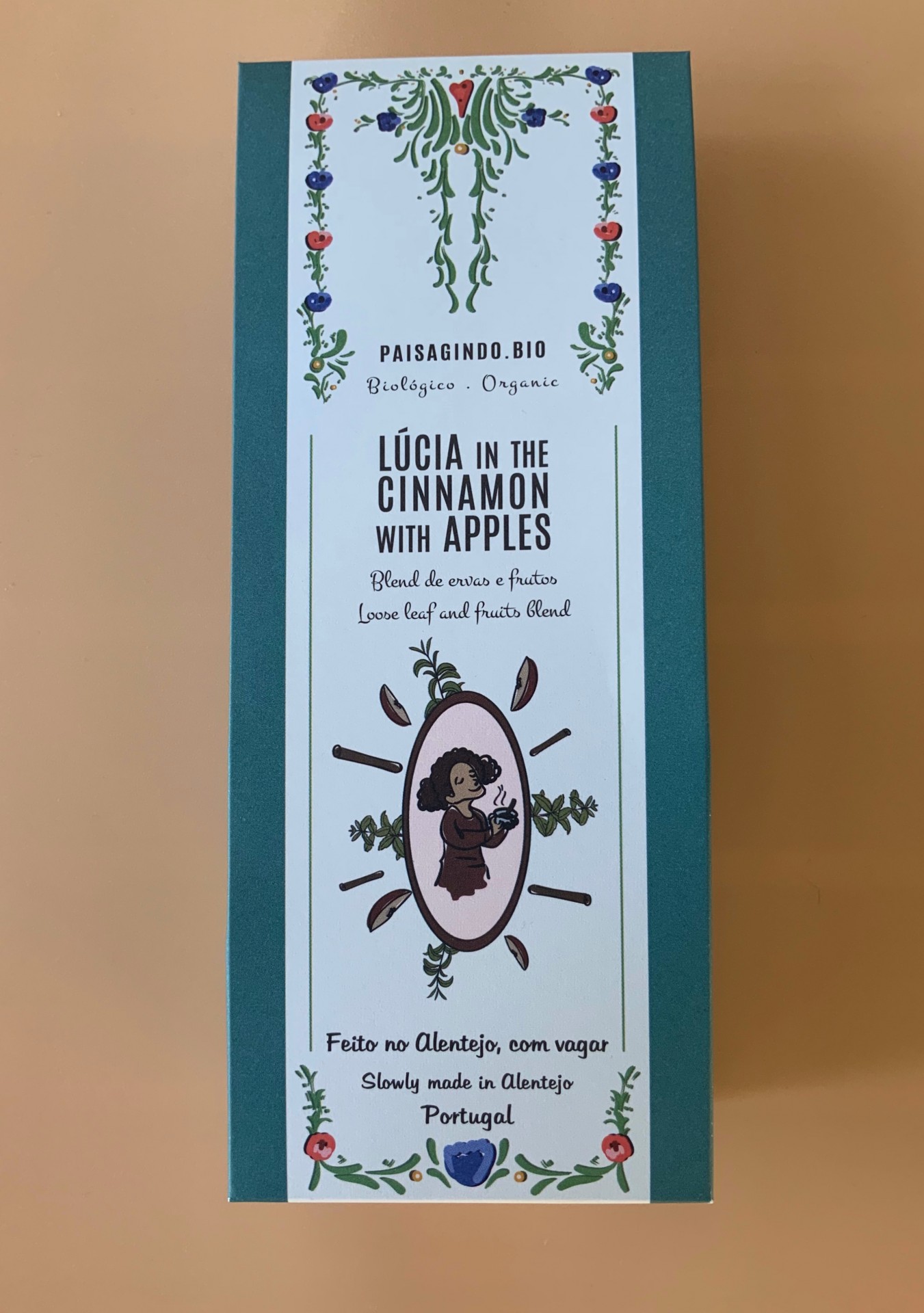 Caixa de chá orgânico LÚCIA IN THE CINNAMON WITH APPLES com design floral e texto bilingue