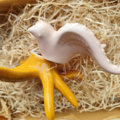 Figura decorativa de pássaro e base em cerâmica sobre fibras naturais.