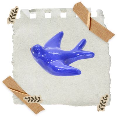 Pássaro decorativo azul em cerâmica sobre papel branco preso com fita adesiva