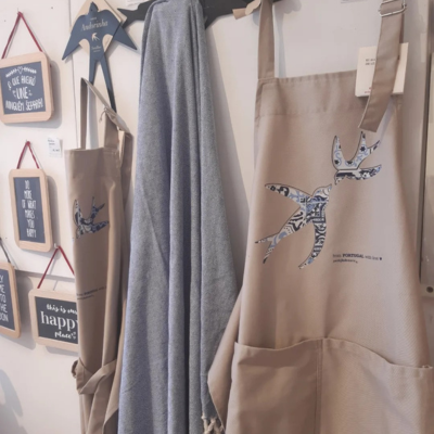 Aventais bege com desenho de pássaro e frases em quadros de madeira na parede