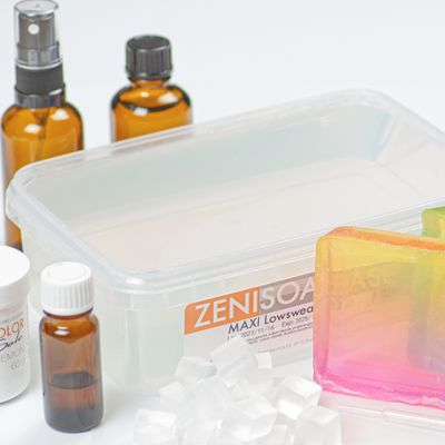 Frascos de vidro âmbar, caixa plástica com etiqueta ZENISOAP MAXI e barras de sabão coloridas