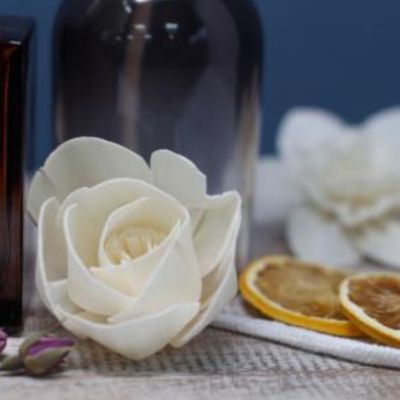 Flor branca artificial com frasco de vidro e fatias de laranja secas