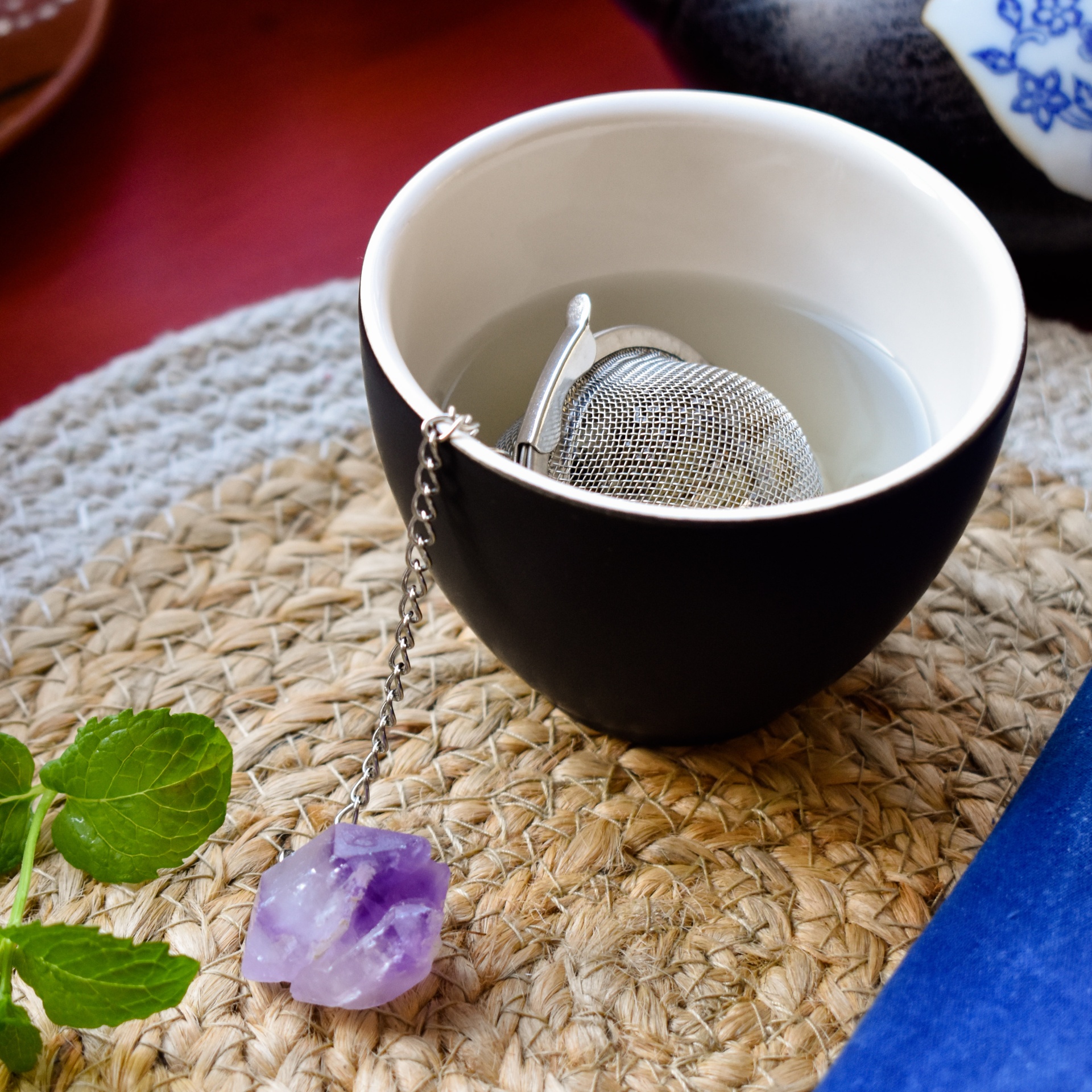 Chávena preta com infusor de chá metálico e pedra roxa