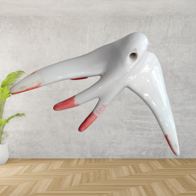 Escultura branca com manchas vermelhas, forma orgânica e planta em vaso branco ao lado