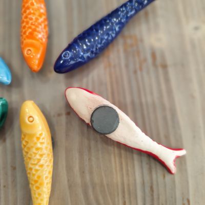 Peixes de cerâmica coloridos sobre superfície de madeira clara