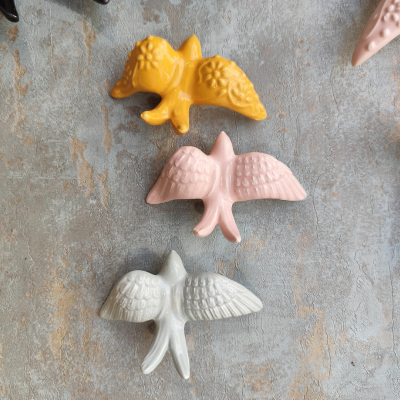 Objetos decorativos em cerâmica em forma de animais com cores amarelo, rosa e branco