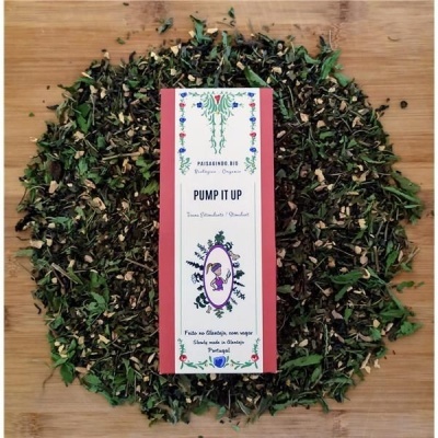 Embalagem de chá orgânico Pump It Up rodeada por ervas secas sobre madeira