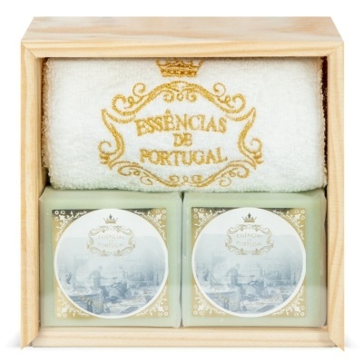 Conjunto de duas velas e uma toalha branca numa caixa de madeira clara.