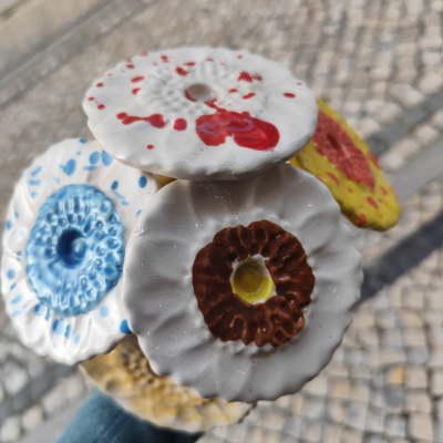 Flores cerâmicas brancas com manchas coloridas em pavimento de pedras