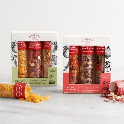 Embalagens de snacks variados em tubos transparentes dentro de caixas brancas com decorações vermelhas