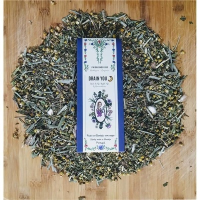 Mistura de ervas e flores secas com rótulo branco azul com texto e ilustração no centro sobre madeira