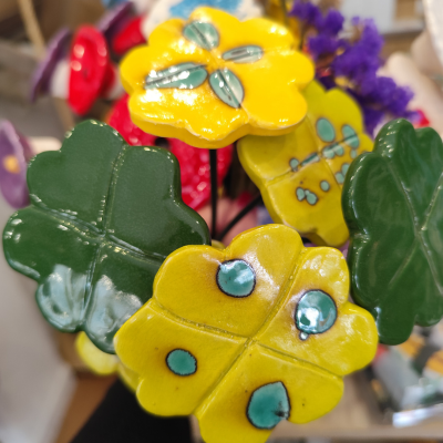 Flores decorativas de cerâmica amarelas, verdes e vermelhas em ambiente interior