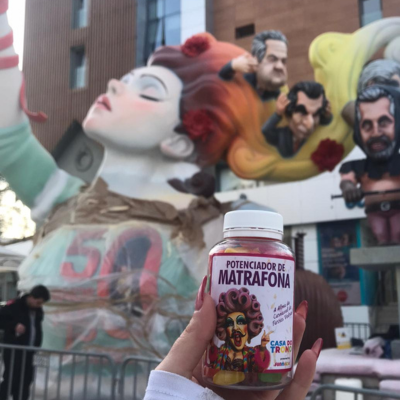 Frasco de suplemento com rótulo colorido em frente a escultura de figuras humanas grandes na rua