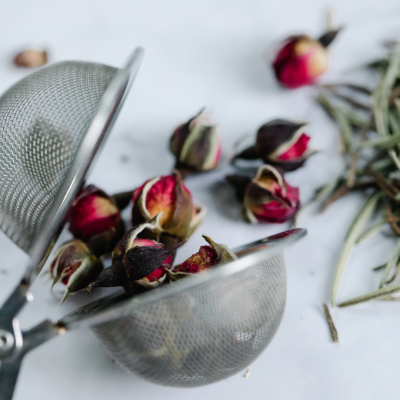 Infusor de chá com botões de rosa secos vermelhos e castanhos