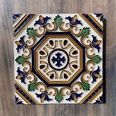 Azulejo cerâmico decorativo com padrão colorido octogonal sobre fundo de madeira