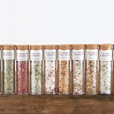 Frascos de vidro com temperos variados em linha sobre mesa de madeira