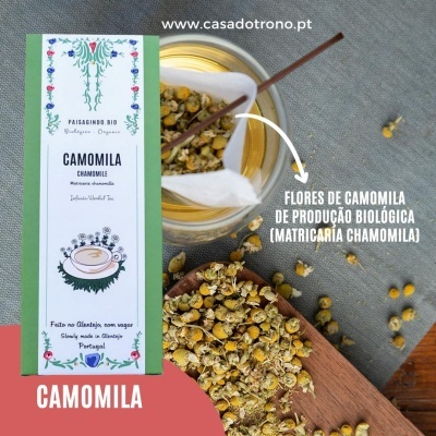 Pacote de chá de camomila orgânica com flores de chá soltas e texto explicativo, em fundo cinza e madeira