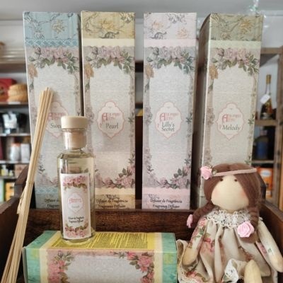 Difusores de fragrância em embalagens florais com boneca de pano ao lado