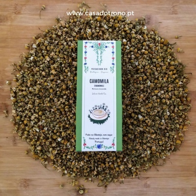Pacote de chá de camomila com flores secas ao redor sobre madeira