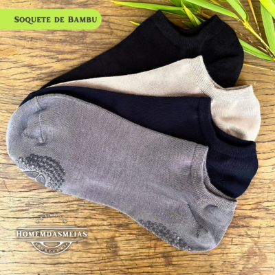 Três pares de soquetes de bambu em preto, bege e cinzento sobre madeira com etiquetas visíveis