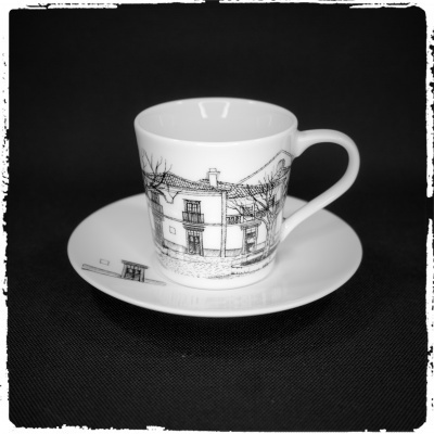 chávena e prato de porcelana branca com desenho a preto de edifícios