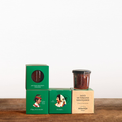 Embalagens verdes e creme com frasco de doce de tomate em cima sobre mesa de madeira