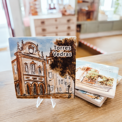 Azulejos coloridos com ilustração e texto Torres Vedras sobre mesa de madeira.