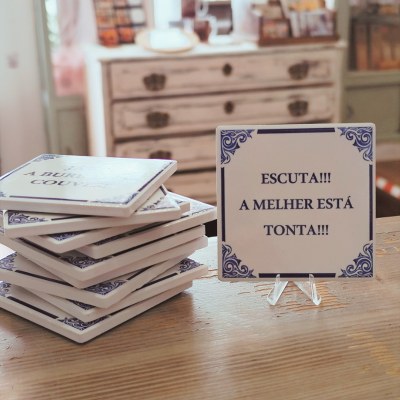 Azulejo com texto em português sobre mesa de madeira e móveis ao fundo