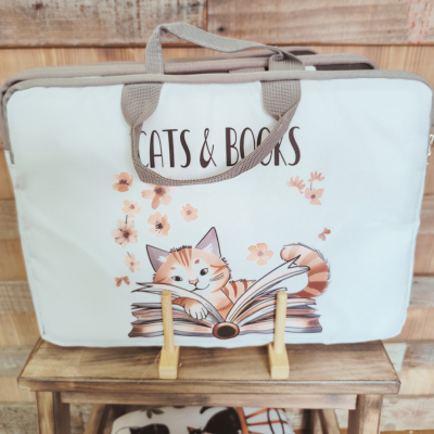 Bolsa branca com desenho de gato e livro, texto 'CATS & BOOKS', fundo de madeira
