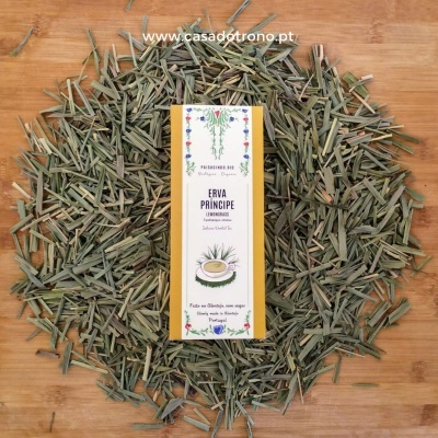 Caixa de infusão de erva príncipe rodeada por erva seca verde sobre madeira