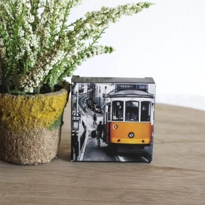 Cubo decorativo com imagem de elétrico amarelo vintage ao lado de vaso com plantas