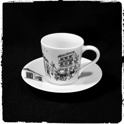 Chávena de café branca com pires e ilustrações a preto