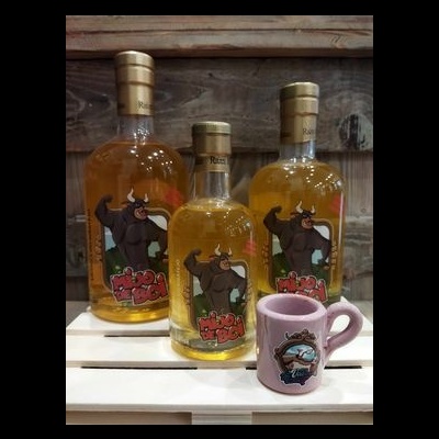 Três garrafas com bebida e rótulo de touro, com caneca rosa à frente