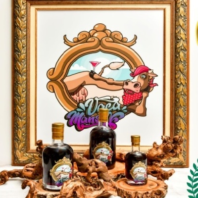 Garrafa de licor com rótulo colorido sobre madeira, quadro com desenho de vaca