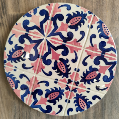 Prato decorativo redondo com padrão floral azul e rosa sobre fundo branco