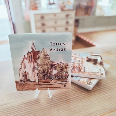 Azulejos decorativos com desenho urbano e texto 'Torres Vedras' sobre suporte em madeira