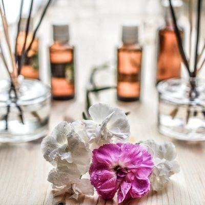 Flores brancas e rosa com gotas de água e frascos de aromatizador