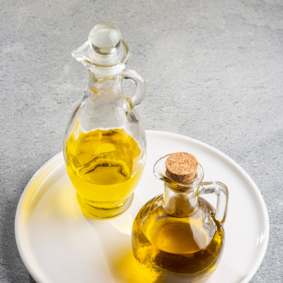 Duas garrafas de vidro com óleo amarelo sobre prato branco