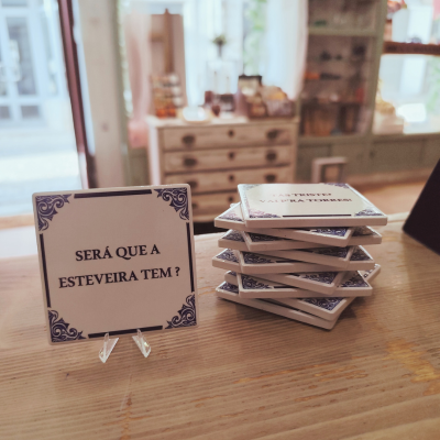 Azulejos decorativos quadrados com texto em português sobre superfície de madeira