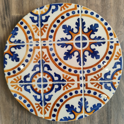 Conjunto de quatro azulejos cerâmicos com padrão circular azul e laranja.