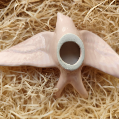 Castiçal rosa em forma de pássaro sobre palha seca