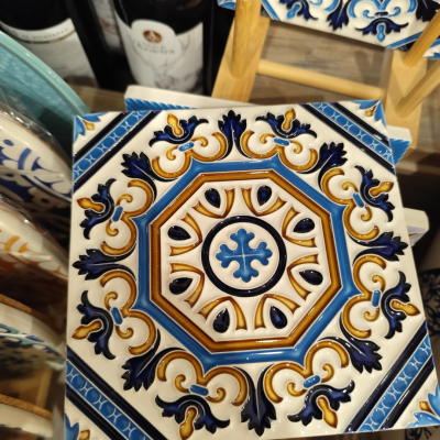 Azulejo cerâmico decorativo azul, castanho e branco com padrão geométrico e floral