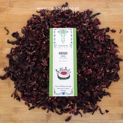 Pacote de chá de hibisco com pétalas secas em fundo de madeira